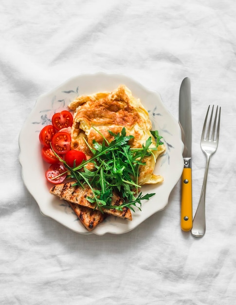 Cheese omelette arugula cherry tomatoes whole grain toast delicious breakfast on a light background top view