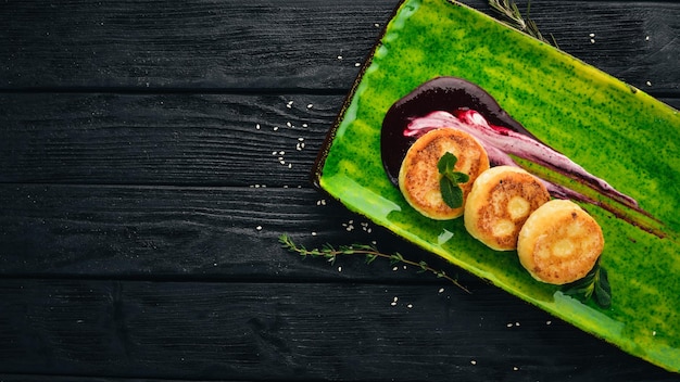 Cheese pancakes with sour cream and berry sauce Dessert On a black wooden background Copy space