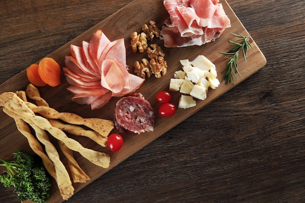 Cheese, parma ham, salami, sirloin, sausage with olives and spices on wooden board.