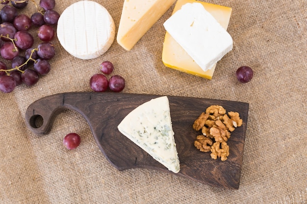 Cheese party table, perfect holiday appetizer with nut on rustic wooden board.