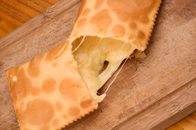 Cheese pastry cut with melted cheese falling onto a board