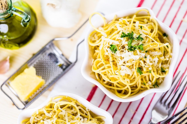 Спагетти с сыром и перцем с зеленым гарниром в белых мисках.