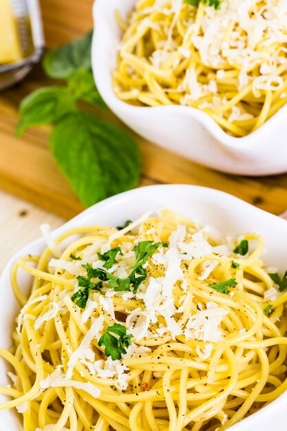 Cheese and pepper spaghetty with green garnish in white bowls.