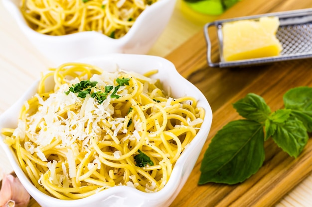 Cheese and pepper spaghetty with green garnish in white bowls.