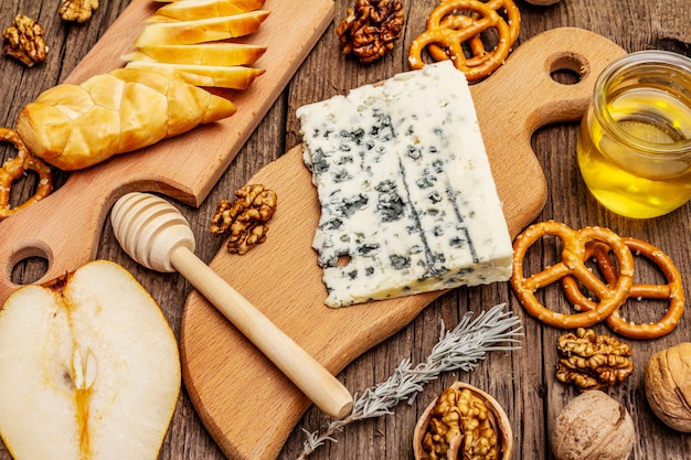 Antipasti di formaggi con formaggio affumicato e erborinato, cracker, miele, noci e pera matura. ricetta spuntino tradizionale