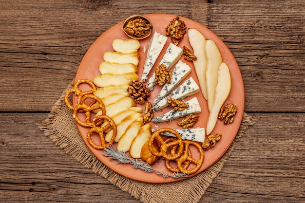 Antipasti di formaggi con formaggio affumicato e erborinato, cracker, miele, noci e pera matura. ricetta spuntino tradizionale