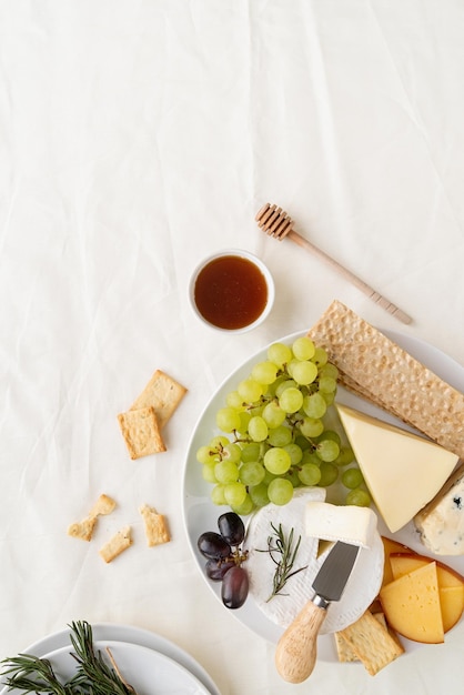 Cheese plate assortment served with honey grapes bread and rosemary