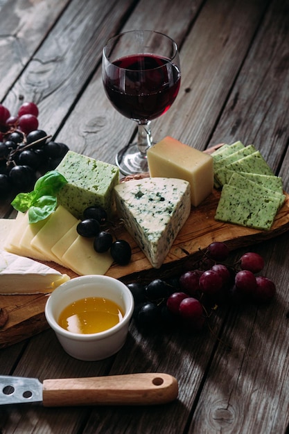 Cheese plate on a dark background. brie, dor blue, gouda,
grapes, nuts, wine