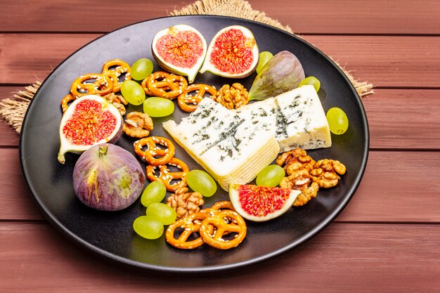 Cheese plate with blue cheese, honey, walnuts, figs, grapes, pretzels