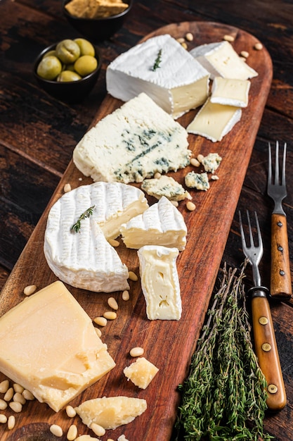 Cheese plate with camembert brie gorgonzola parmesan olives\
nuts and crackers wooden background top view