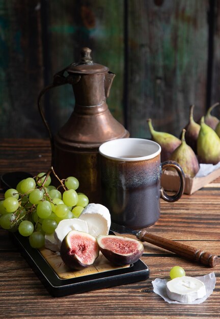 Сырная тарелка с козьим сыром, виноградом и инжиром, медный чайник, угол зрения