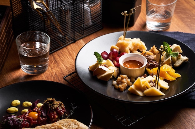 Cheese plate with grapes and honey on wooden table