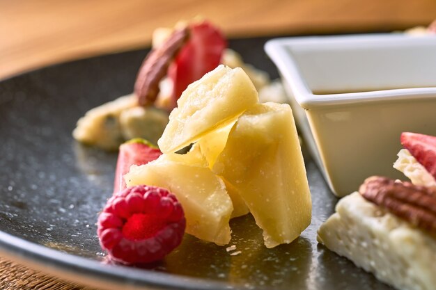 Cheese plate with honey, nuts and strawberries. Close up view on hard cheese