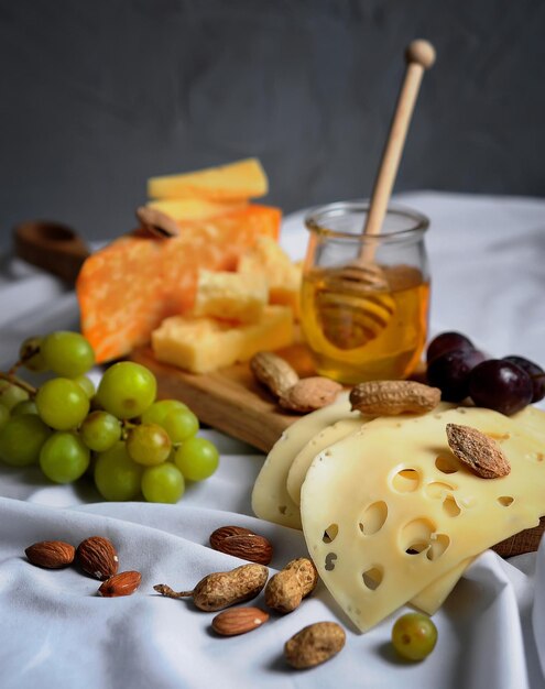 Foto piatto di formaggi con frutta a guscio e miele su sfondo grigio