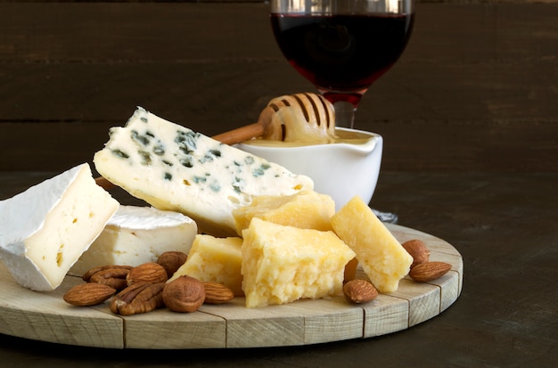 Cheese plate with nuts and honey on dark background.