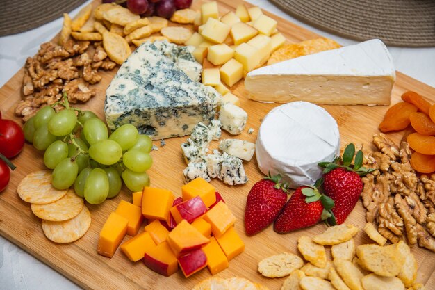 Cheese plate with variety of appetizers on table. Strawberry, apricot, grape and grain cheese dishes on the table