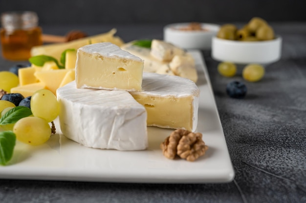 Cheese plate with a variety of cheeses honey grapes nuts olives blueberries  A festive snack