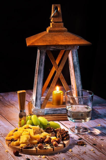 Cheese plate with a variety of snacks on the table with two glasses of wine by candlelight