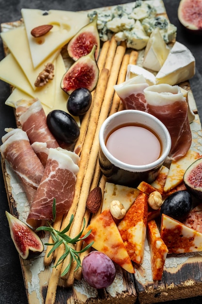 Cheese platter assorted cheese wine ham fruit bread sticks nuts\
food recipe background close up top view