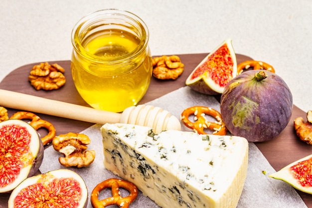 Cheese platter (board) with blue cheese, honey, walnuts, figs, pretzels