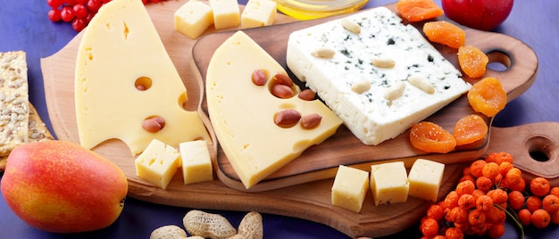 Cheese platter variety of cheeses on wooden plate with fruits and nuts Hard cheese