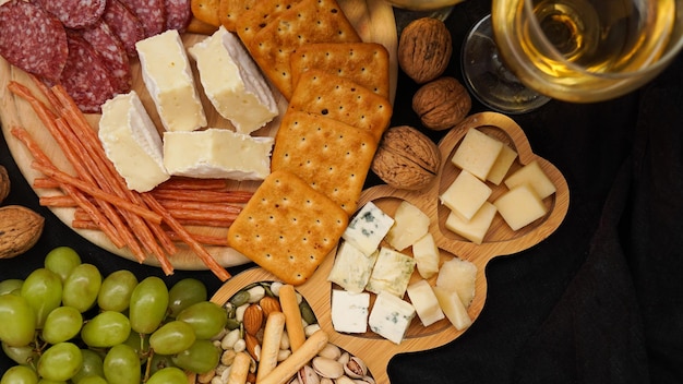 Cheese platter with assorted cheeses grapes nuts over black background