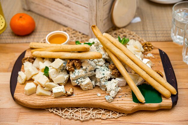 Foto piatto di formaggio con gorgonzola, formaggio blu, noci e miele, pochi bastoncini di pane.