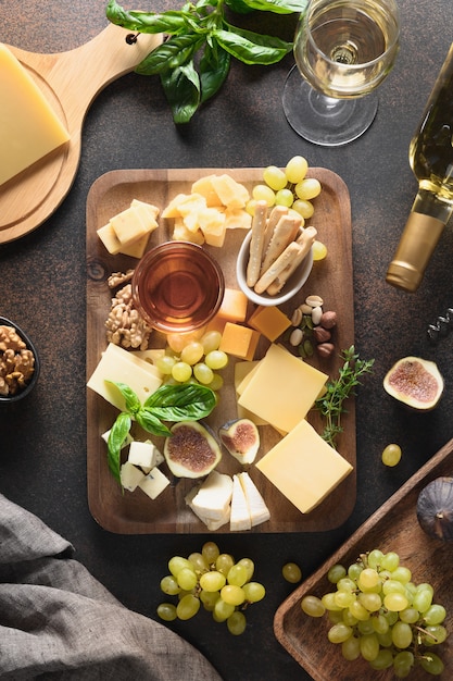 Cheese platter with grapes nuts figs on brown background top view