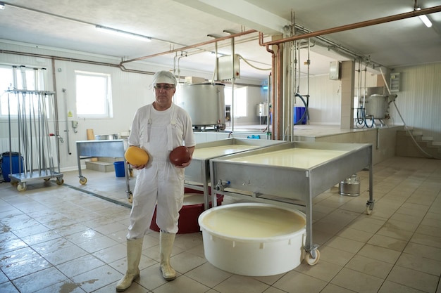 Cheese production male cheesemaker employee working in factory