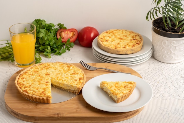 Cheese quiche a pie on a wooden board a slice of the pie on a white plate