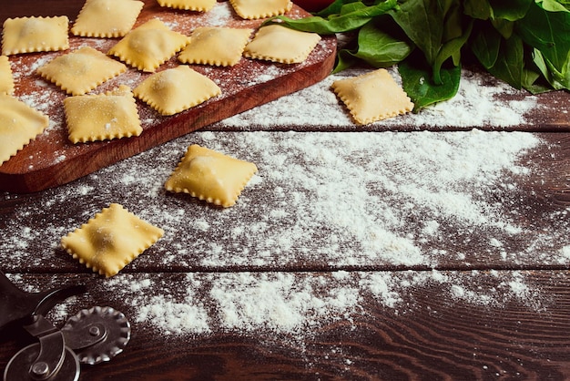 Ravioli al formaggio con spinaci e formaggio con ingredienti su un tavolo di legno orizzontale senza messa a fuoco selettiva di persone