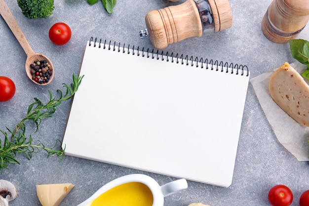 Cheese sauce with ingredients and blank notebook on light background