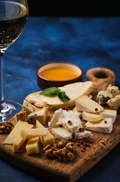 Cheese set with honey and nuts. Assortment of cheeses on a wooden board. Cheese appetizer set.