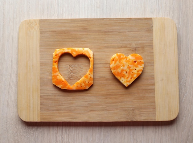 Cheese slice with cut in shape of heart on wooden background