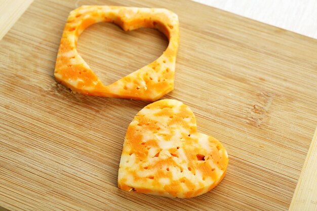 Foto fetta di formaggio con taglio a forma di cuore su fondo di legno