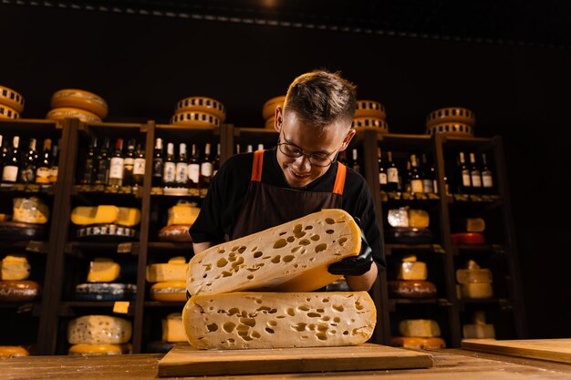 Cheese sommelier in food shop worker looking at limited maasdam\
natural aged and check quality handsome bearded man working in food\
store