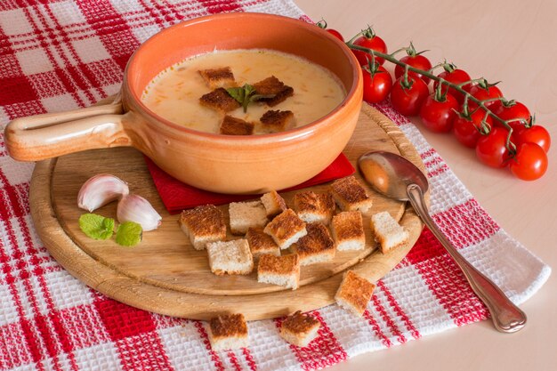 Cheese soup with crackers, cherry tomatoes and garlic