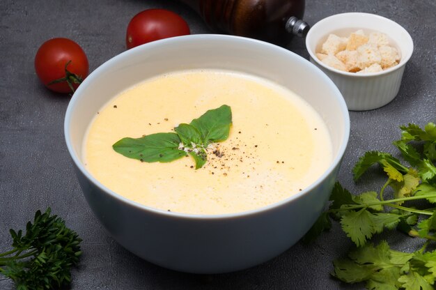 Cheese soup with croutons, basil and black pepper