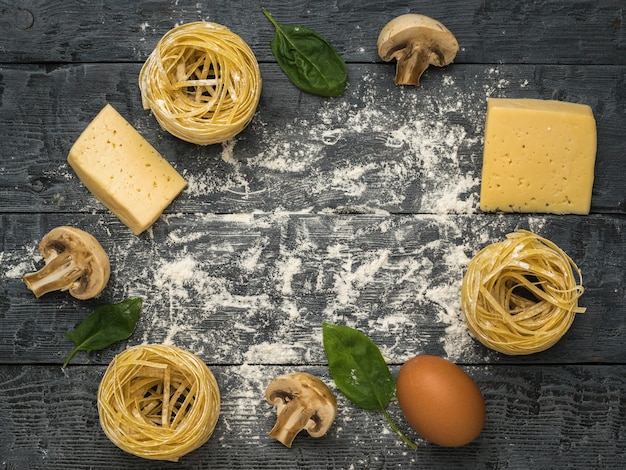 Сыр, шпинат, макаронные изделия и грибы на деревянном столе. Место для текста. Ингредиенты для приготовления макаронных изделий.