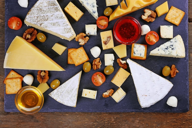 Cheese for tasting on wooden background top view