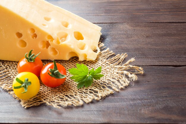 Cheese and tomatoes on dark wooden table 