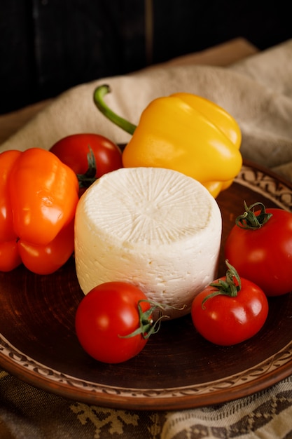 Cheese, tomatoes and peppers on pottery plate