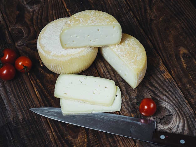 Cheese wheel and pieces of cheese on a wooden table