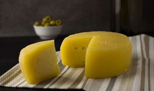 Cheese wheel with a cut piece on a napkin