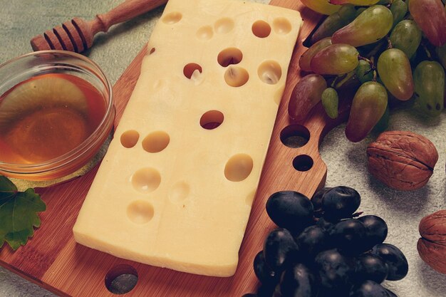 큰 구을 가진 치즈 Emmental Maasdam 브리 치즈 포도와  견과류와 함께 절단 보드에 와인 보기