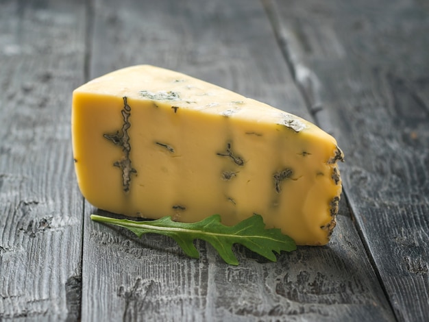 青いカビとルッコラと木製のテーブルの上のチーズ。チーズの繊細さ。便利なカビ