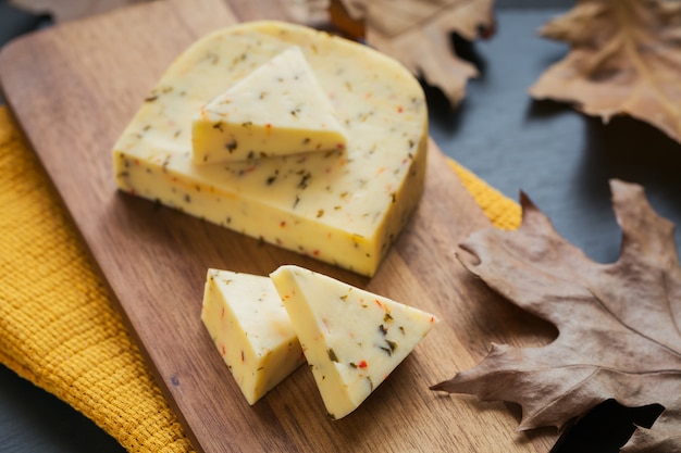 Cheese with herb in a cutting board on dark background