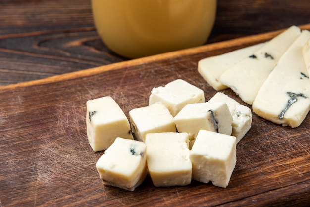 Cheese with mold on dark wooden background.