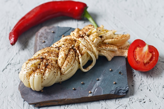 Cheese with spices on a stone stand. Suluguni cheese, tomatoes, pepper