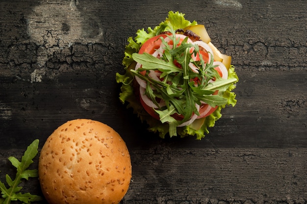 Cheeseburger su una vecchia superficie di legno di colore scuro hamburger con carne e pomodoro